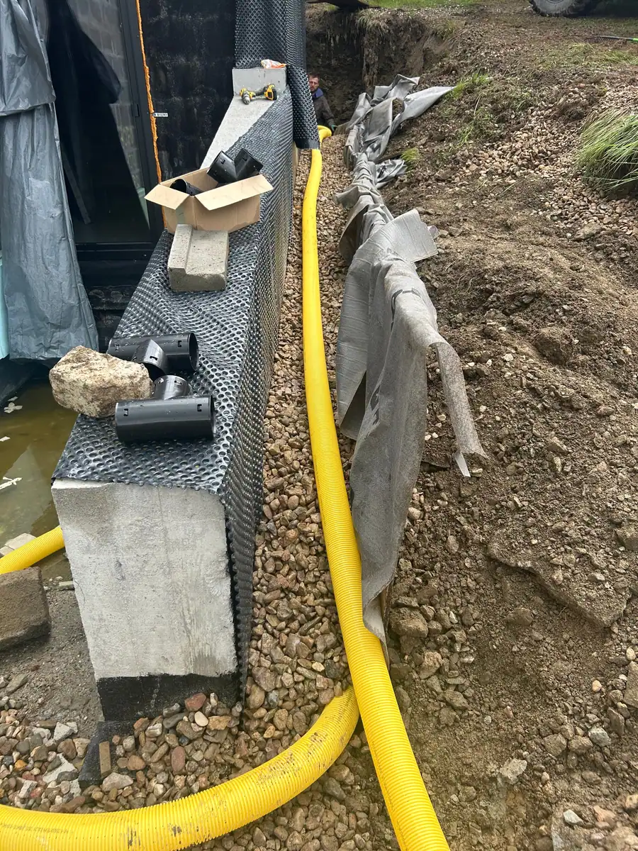 Drenaż opaskowy przy ścianie fundamentowej z folią kubełkową i obsypką z kruszywa