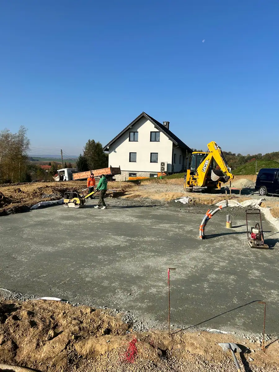 Zagęszczanie podbudowy pod płytę fundamentową zagęszczarkami płytowymi, w tle koparko-ładowarka JCB 3CX