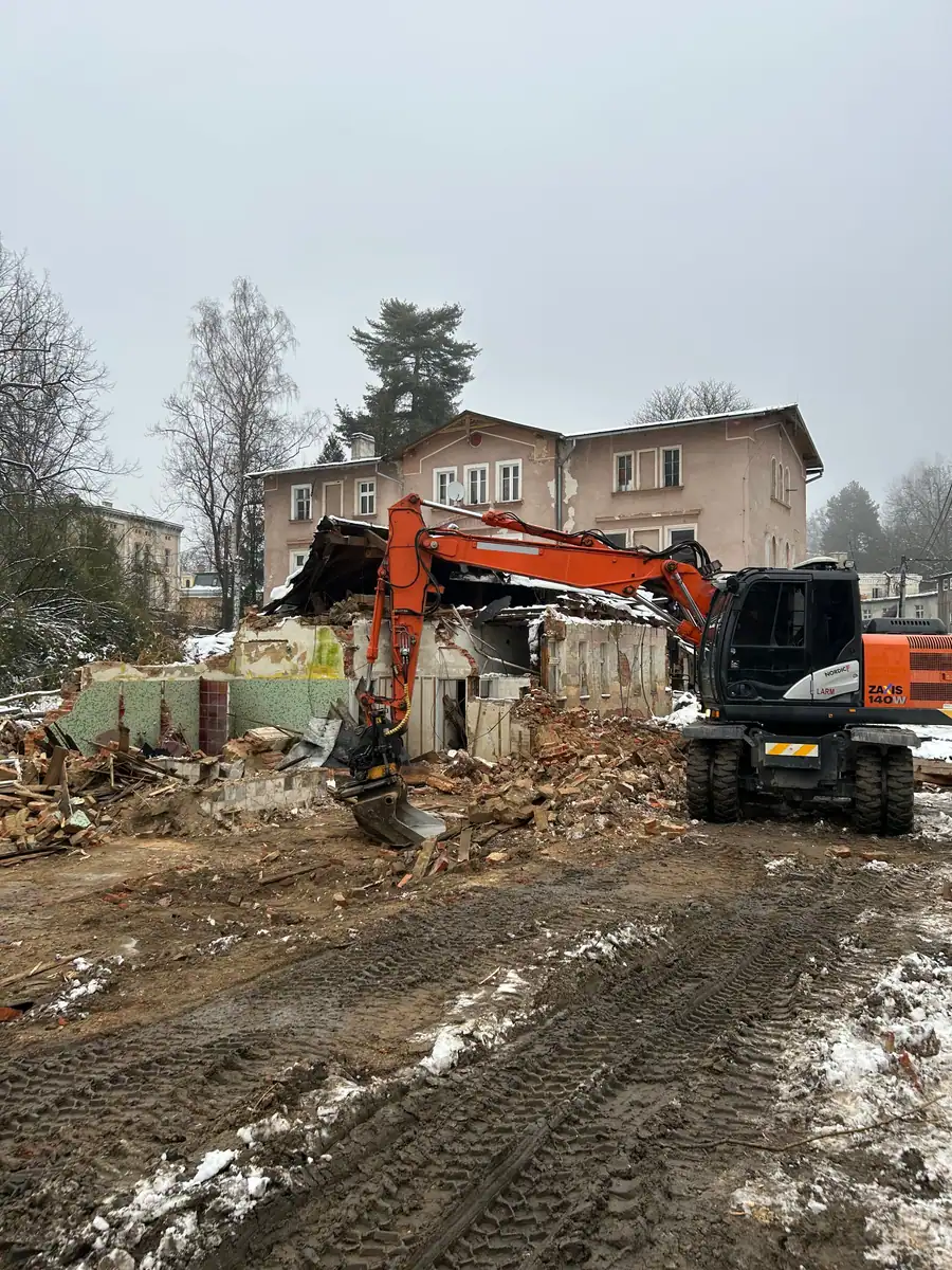 Koparka kołowa Hitachi Zaxis 140W rozbiera murowany budynek gospodarczy zimą