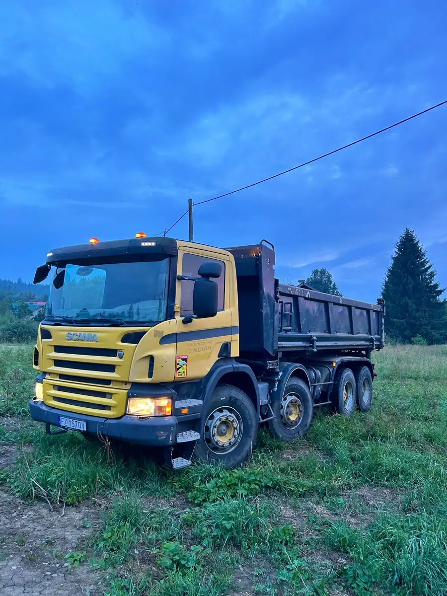 Czteroosiowa wywrotka Scania P 8×4 ze skrzynią wywrotczą na łące o zmierzchu