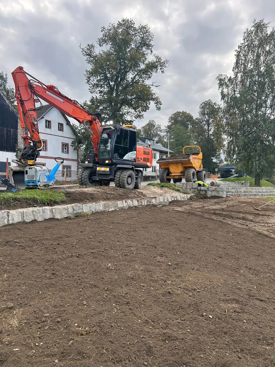 Koparka kołowa Hitachi Zaxis 140W i wozidło Wacker Neuson rozkładają ziemię ogrodową przy krawężnikach