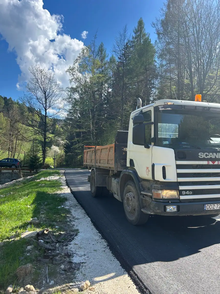 Wywrotka Scania 220 4×2 na drodze dojazdowej w dolinie, przy świeżo ułożonej nawierzchni