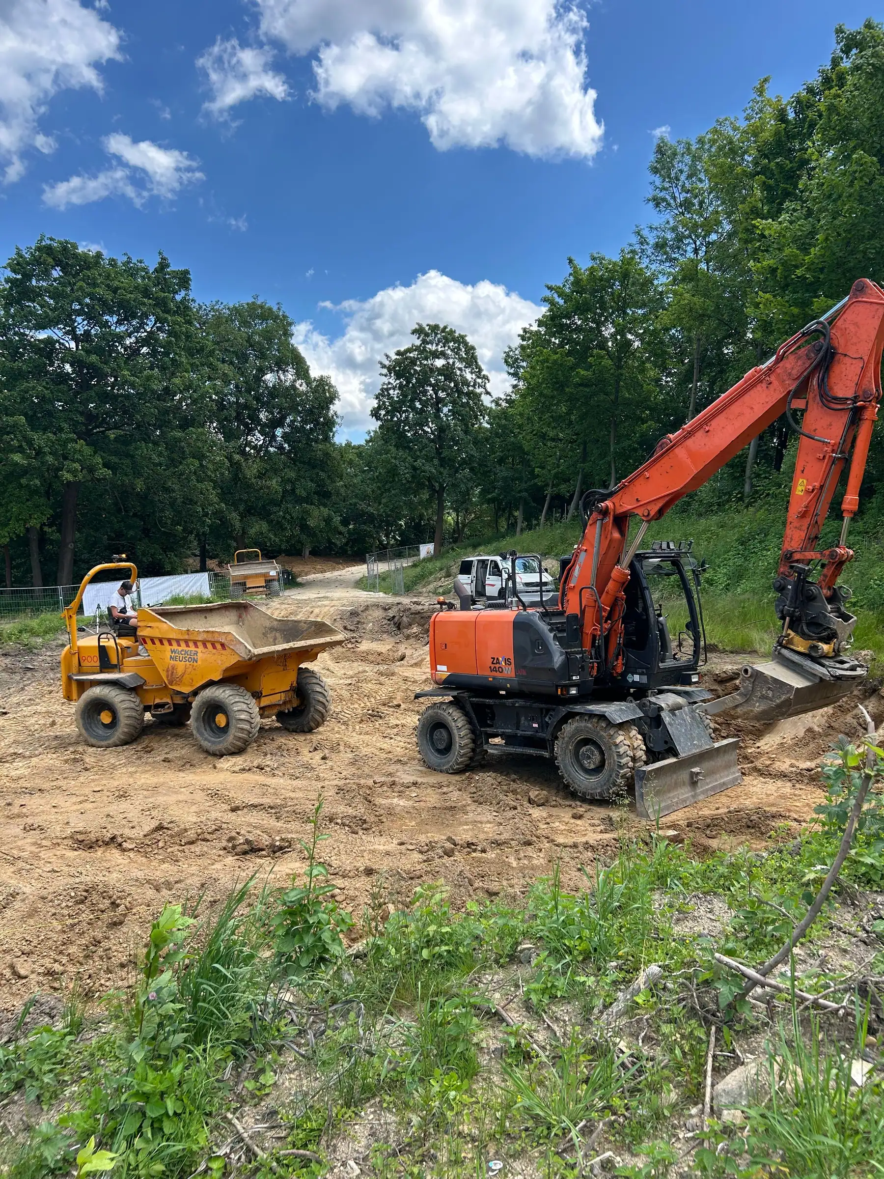 Koparka kołowa Hitachi Zaxis 140W z tiltrotatorem i wozidło Wacker Neuson przy wykopie na zboczu
